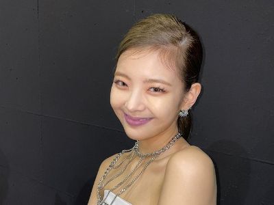 Choi Jisu is smiling as she is wearing a white dress in the picture.